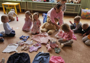 Pani z dziećmi i różnymi ubraniami na dywanie