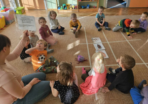 dzieci patrzą na obrazek siedzą z panią w kole na dywanie