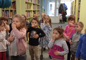 grupa dzieci zasłania swoje usta