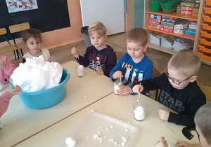 dzieci badają śnieg na stole