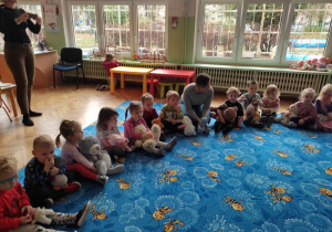 dzieci siedzą na dywanie trzymając pluszowe misie