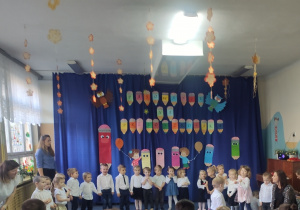 grupa dzieci z kadrą pedagogiczną na tle dekoracji