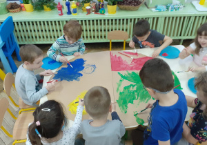 dzieci malują duży owal z szarego papieru na 4 kolory