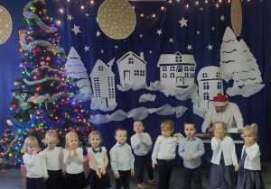 występ dzieci na tle świąteczno-zimowej dekoracji