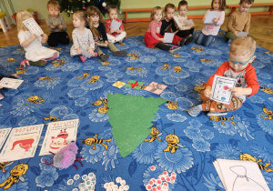 grupa dzieci na dywanie ze świątecznymi obrazkami