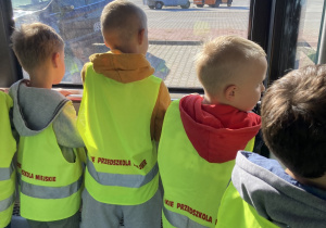 Dzieci oglądają lotnisko przez szybę autobusu