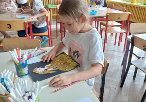 dziewczynka układa obrazek z suszonych liści