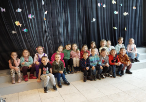 grupa dzieci siedzi na tle dekoracji