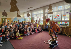 akrobacje prowadzącej z przedmiotami cyrkowymi przed widownią dzieci