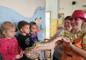 prowadząca trzyma węża na rękach i pokazuje dzieciom
