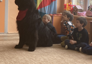 czarny pies siedzi obok dzieci