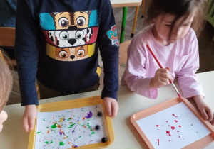 dzieci wykonują prace plastyczna farbami