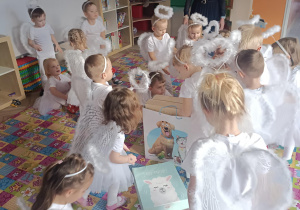 grupa dzieci w przebraniach aniołów z prezentami
