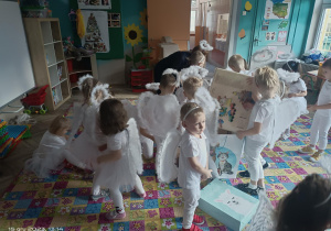 dzieci w strojach aniołów rozpakowują prezenty
