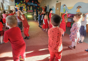 dzieci tańczą z podniesionymi w górę rękami