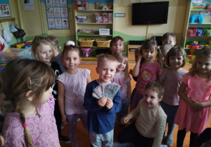 chłopiec trzymający banknoty z grupą dzieci