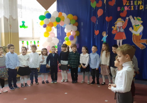 dzieci w półkolu na scenie śpiewają