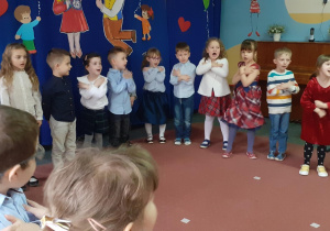 dzieci śpiewają piosenkę i trzymają ręce na ramionach