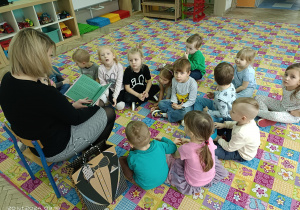 Prowadząca zajęcia czyta dzieciom książkę