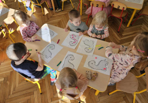 Dzieci wyklejają dinozaura plasteliną