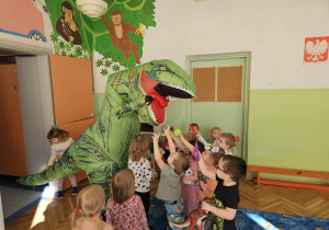 dzieci celują piłkami w paszczę dinozaura
