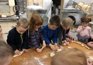 dzieci wyrabiają ciasto chlebowe na małe chlebki