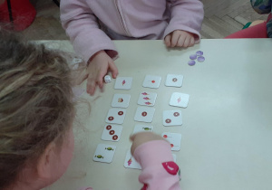 elementy gry na stole i widoczne ręce dzieci