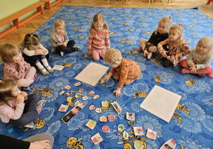 dzieci z małymi obrazkami na dywanie