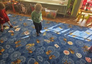 chłopiec idzie po dywanie pomiędzy obrazkami