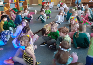 Grupa dzieci kręci się na pośladkach siedząc na podłodze