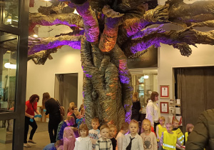dzieci stoją pod drzewem w holu teatru