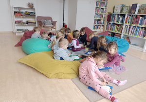 grupka dzieci koloruje obrazki na dywanie