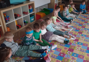 dzieci siedzą na dywanie i prezentują kolorowe skarpetki