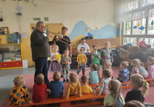 Dzieci przyglądają się grającemu na puzonie muzykowi
