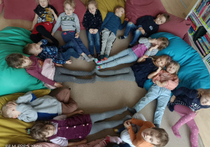 Dzieci leżą w kręgu opierając się o poduchy