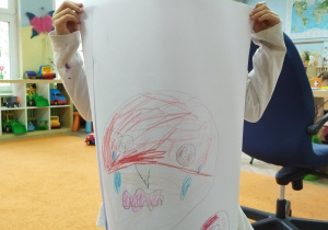 Dziewczynka trzyma duży rysunek postaci odczuwającej złość