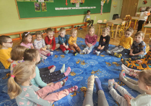 Dzieci siedzą w kręgu z wyciągniętymi nogami pokazując swoje skarpetki