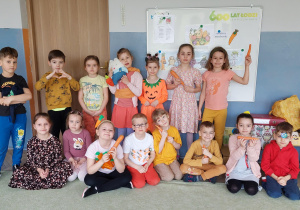 Dzieci z grupy Żuczki pozują do zdjęcia z marchewkami w rękach