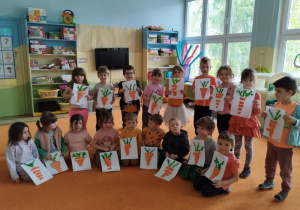 Dzieci pokazują prace plastyczne przedstawiające marchewki