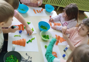 Dzieci wykonuja marchewki z papieru i bibuły