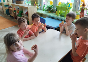 Dzieci przy stole jedzą ciasto
