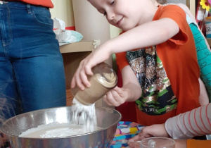 chłopiec wsypuje mąkę do miski