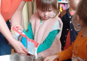 Dziewczynka wsypuje mąkę do szklanki
