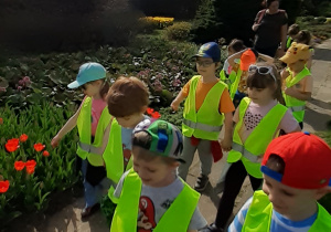 Dzieci spacerują alejką przy kwiatach