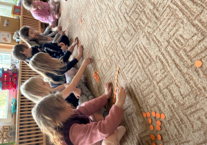 dzieci układają kształt marchewki z pomarańczowych kółek