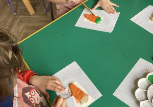dziewczynki malują farbami marchewki z masy solnej