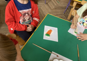 dziewczynka prezentuje pomalowaną marchewkę