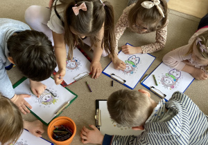 grupka dzieci koloruje ilustracje Wróżki Zębuszki