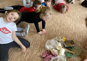 dzieci oglądają zgromadzone na dywanie "śmieci"