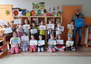 dzieci prezentują wykonane przez siebie projekty logo firmy